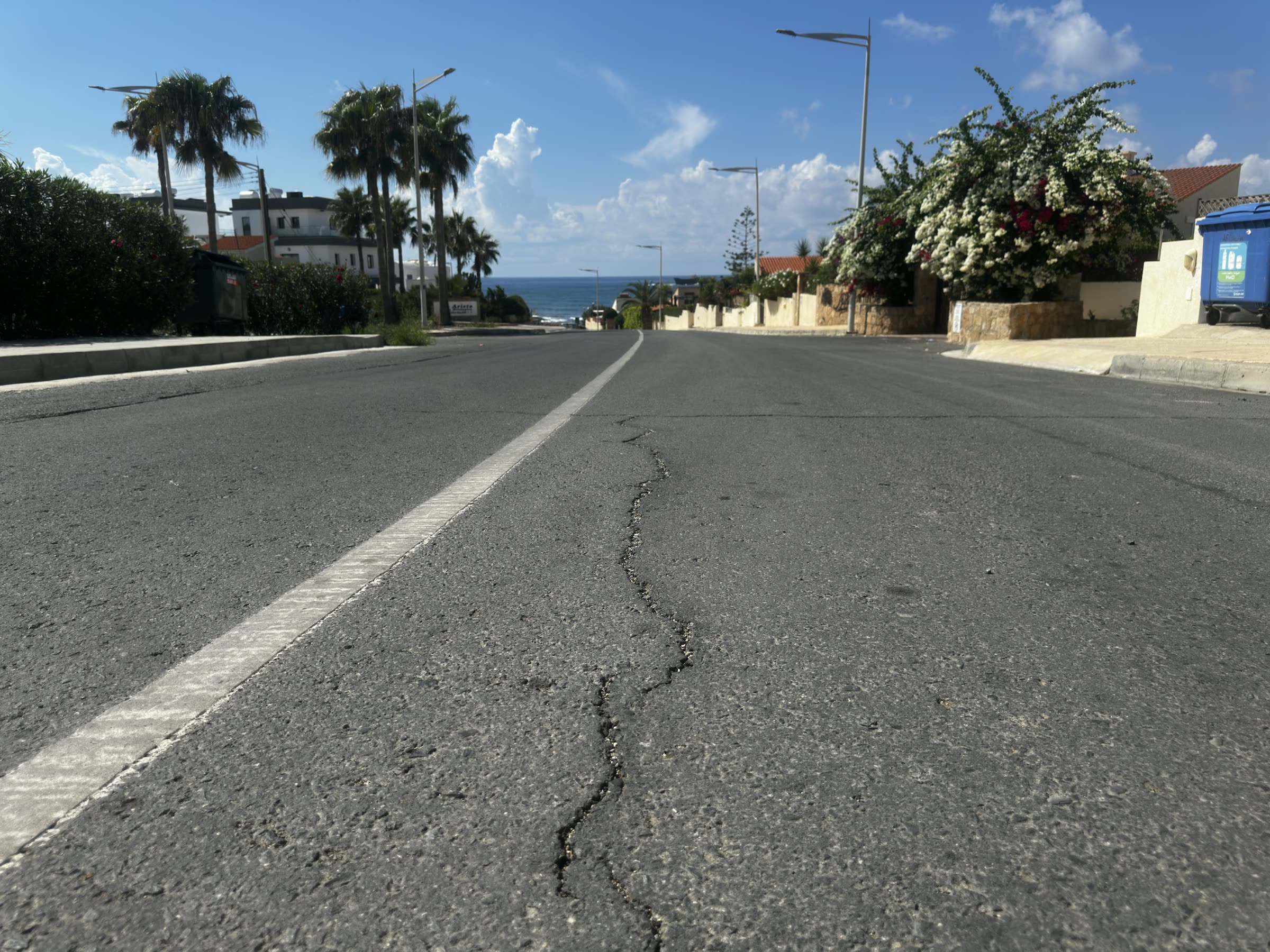 A cracked road descending toward the sea
